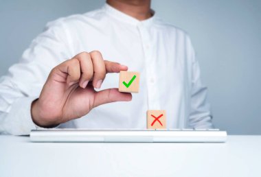 Yeşil işaret simgesi, iş adamının elindeki tahta küp bloğunda ve klavye bilgisayarındaki kırmızı haç sembolünde. Doğru ya da yanlış zihniyet, doğru, seçim yapmak, evet ya da hayır.