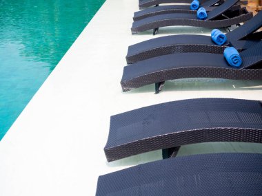 Misafir için mavi havuz boş modern rattan güneş yatağı beyaz mermer zemin üzerinde bir otel havuzunda yüzme, tatil konsepti.