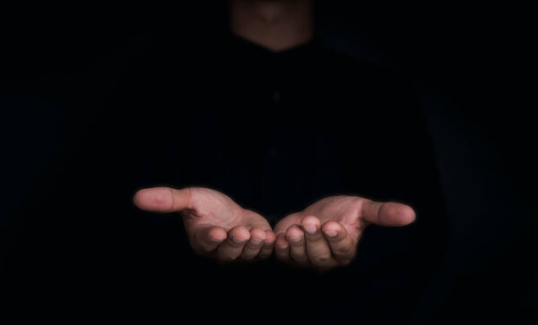 Give two hands with nothing on both on dark background with copy space. Close-up receiving gesture of outstretched cupped empty open hands. Concept of giving, donation, receiving, asking, and bribery.