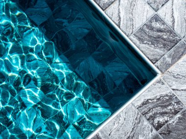 Mermer desenli gri fayanslar, havuz kenarının köşesinde boş alan nesneler için ya da yüzme havuzunun mavi su yüzeyi yakınına yerleştirilmiş yaz ürünleri için. Mozaik güverte kaidesi.