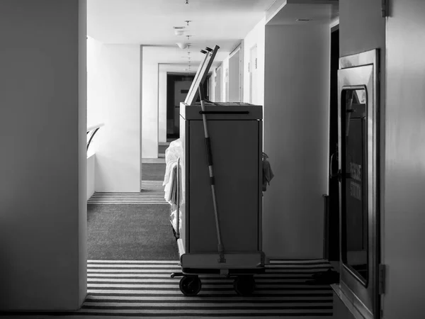 Hotel cleaner cart. Maid trolley on the hallway near the fire extinguisher, rescue station in a luxury hotel with nobody, black and white photography style