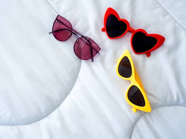 Three Pairs Colorful Sunglasses Red Yellow White Duvet Bed Background —  Fotos de Stock