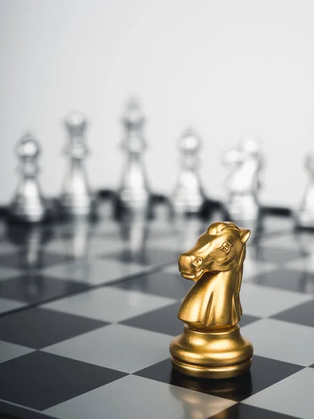 这匹金马 骑士棋子站在棋盘上银制棋子的前面 背景为白色 风格垂直 幸存者 商业战略概念 — 图库照片