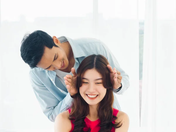 驚くべきことに 甘いカップルの概念 ハンサムなアジア人男オープン手後にカバー彼のガールフレンドの目の幸せかなり笑顔女の子作る驚きでベッドルームでホワイトカーテンの背景 — ストック写真