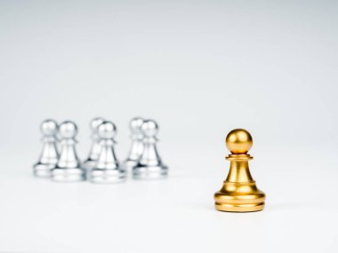 The golden pawn chess piece standing out from the group of silver pawn chess pieces on white background, stand out from the crowd. Leadership, Unique, influencer, difference concept.