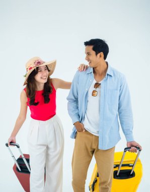 Birkaç gezgin, arkadaşlarla mutlu tatiller. Yaz tatili. Genç Asyalı kadın ve erkek birbirlerine gülümseyerek bakıyorlar, beyaz arka planda izole edilmiş bavullarla yürüyorlar, dikey bir şekilde..