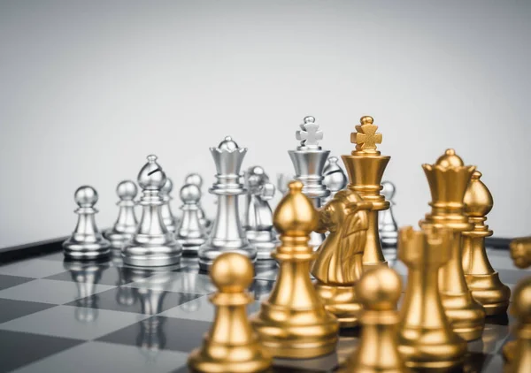 Set of gold and the silver chess pieces, king, rook, bishop, queen, knight, and pawn standing together on the chessboard. Leadership, fighter, competition, confrontation, and living together concept.