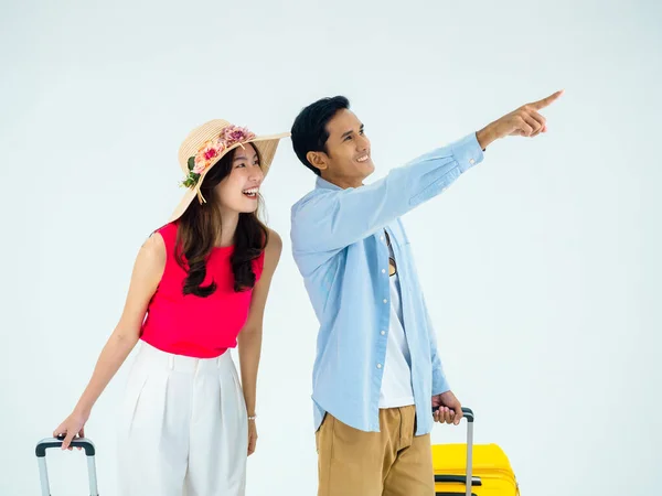 Exciting travel, happy holiday. Summer vacation. Asian couple travelers looking out gestures with exciting, young man and woman pointing and walking with suitcases, isolated on white background.