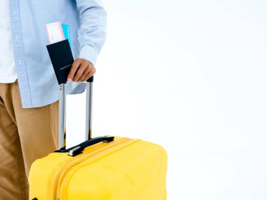 Tökezlemeye hazır. Pasaport, kot pantolonlu bir gencin elinde, beyaz arka planda izole edilmiş sarı bir bavul tutarken ve yürürken. Gezgin ya da turist.