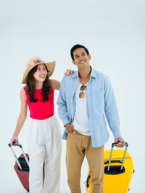 Birkaç gezgin, arkadaşlarla mutlu tatiller. Yaz tatili. Renkli kostümlü genç Asyalı erkek ve kadın rahat görünüyor, beyaz arka planda izole edilmiş bavullarla yürüyorlar, dikey tarzda..