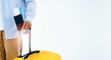 Tökezlemeye hazır. Pasaport, kot pantolonlu bir gencin elinde, beyaz arka planda izole edilmiş sarı bir bavul tutarken ve yürürken. Gezgin ya da turist.