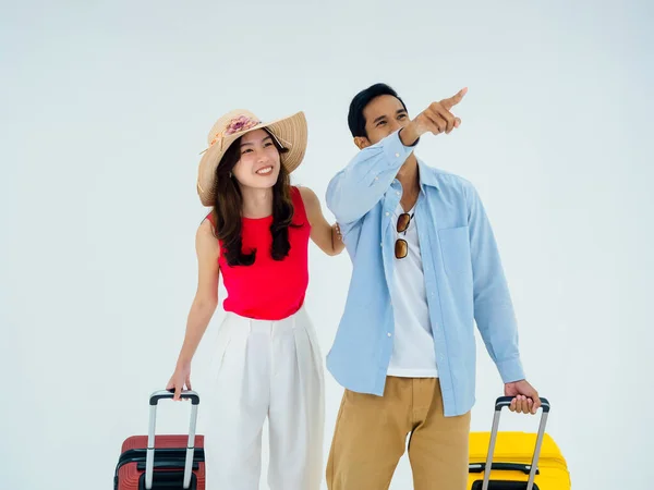 Exciting travel, happy holiday. Summer vacation. Asian couple travelers looking out gestures with exciting, young man and woman pointing and walking with suitcases, isolated on white background.