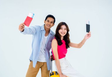 Mutlu tatillerde iki gezgin. Yaz tatili balayı konsepti. Gülümseyen Asyalı çift pasaport tutuyor, gezintiye çıkmaya hazır genç kadın ve bagajlı adam beyaz arka planda izole edilmiş..