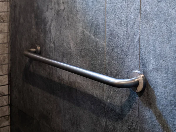 酒店一间残疾人士出入浴室灰色石墙背板上安装不锈钢抓斗扶手的特写照片 — 图库照片