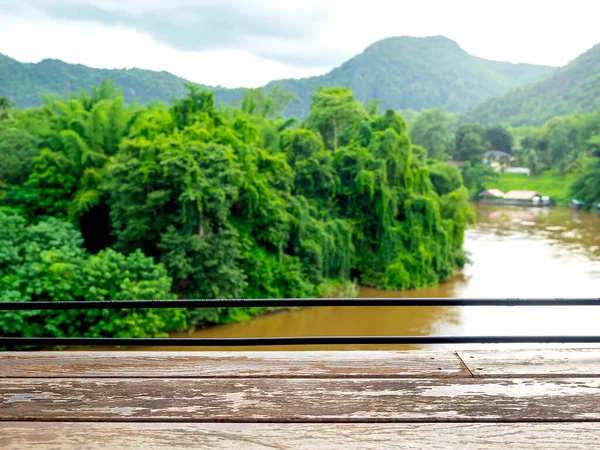 Empty space on old wooden plank table bar on river wild, green tropical forest and. mountain view. Blank space for product display mockup advertising in front of green idyllic blurred water nature.