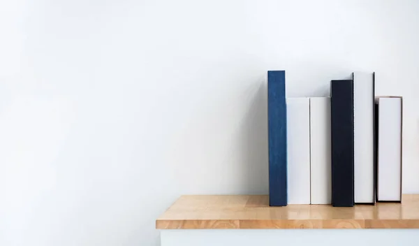 Mockup of white and blue blank book spines on wooden shelf on white background with copy space. Row of books with empty space book names cover, minimal style.