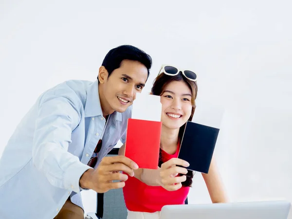 Couple travelers in happy holiday. Summer vacation honeymoon concept. Smiling Asian couple holding and showing passport, ready to trip, young woman and man portraits isolated on white background.