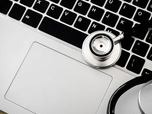 Close up stethoscope on keyboard and touchpad on laptop computer background with copy space, top view. Business, technology, healthcare and medical, fix and repair concept.