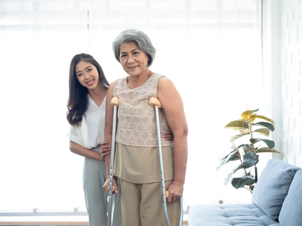 Elderly Woman Trying Walk Crutches Standing Held Supported Arms Young — Photo