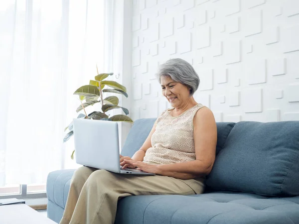 Portrait Smiling Asian Senior Casual Woman Sitting Sofa Working Laptop — Zdjęcie stockowe