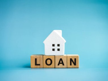 Ev kredileri, konut, bina, ipotek, gayrimenkul yatırım kavramları. Mavi arka planda izole edilmiş, küçük beyaz ev modelinin altındaki tahta bloklara 