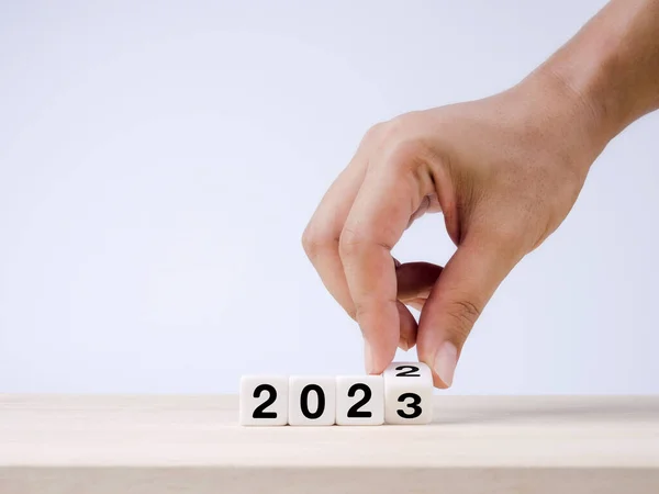 2022历年改为2023年 成功概念 从2022年到2023年 白色立方体块手工旋转 为快乐的圣诞和蓝色背景的新年做准备 — 图库照片