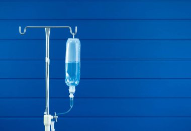 Direkte asılı duran tuz torbası mavi tahta duvarda duruyor. Arka planda kopya alanı var. Serum fizyolojik solüsyonu. Koğuştaki hastaya enfüzyon için serum..