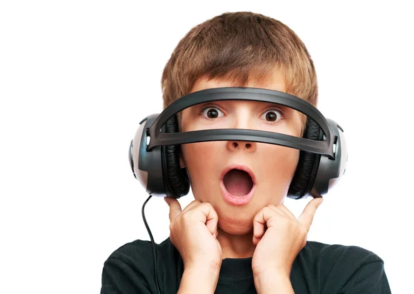 Surprised boy looking through headphones and screams — Stock Photo, Image