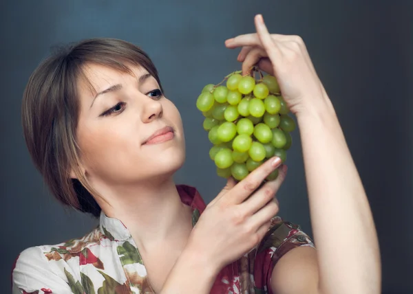 The girl is looking on grapes — Stock Photo, Image