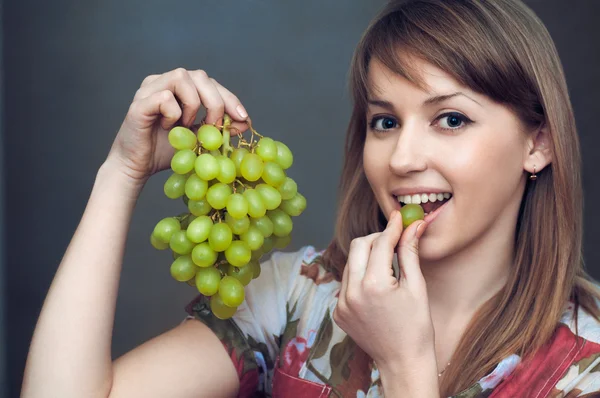 La chica sonriente está comiendo uvas — Foto de Stock
