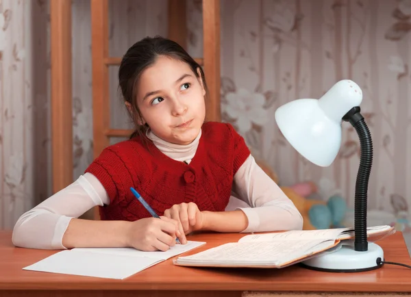 Chica pensativa haciendo la tarea en la mesa — Foto de Stock