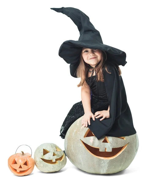 Маленькая ведьма сидит на тыкве — стоковое фото