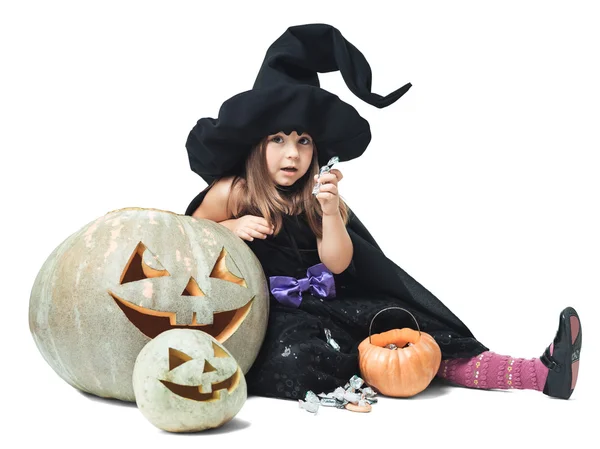 Witch sits near the pumpkins and eating candy — Stock Photo, Image