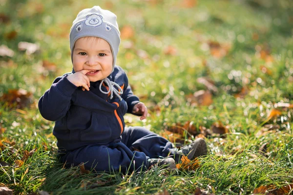 Kleine jongen zittend op het gras — Stockfoto