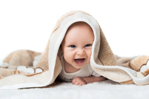 Kleine baby is lachen onder het tapijt — Stockfoto