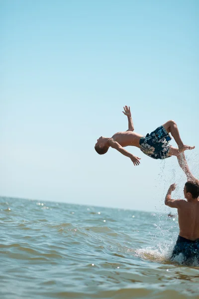 Gruppo di ragazzi in piedi nel mare gettato su uomo — Foto Stock