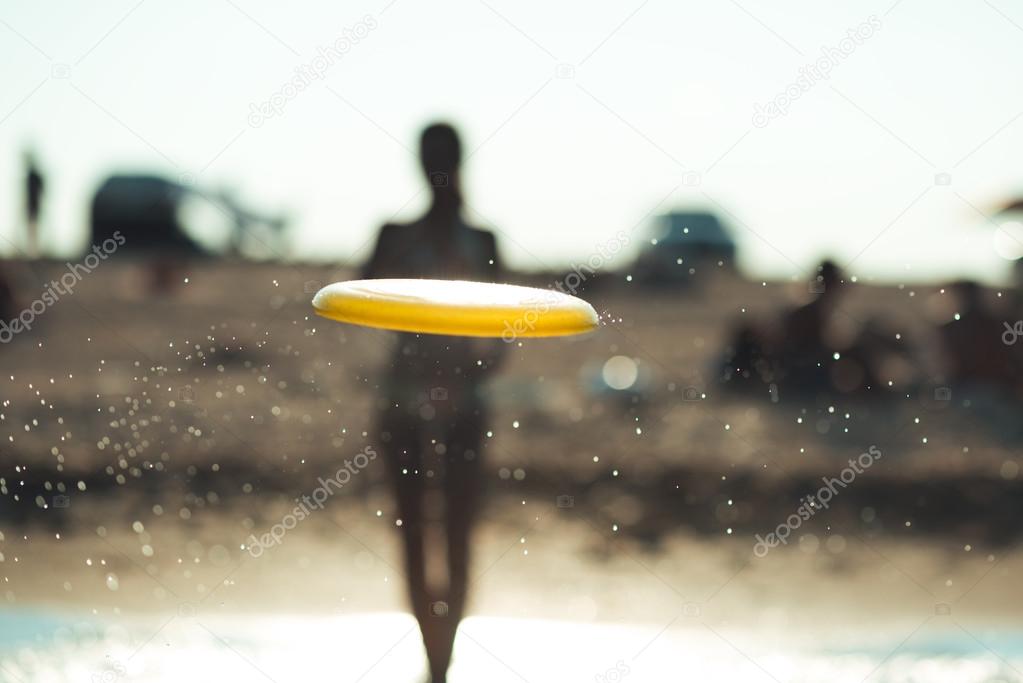frisbee in a spray of water against the beach