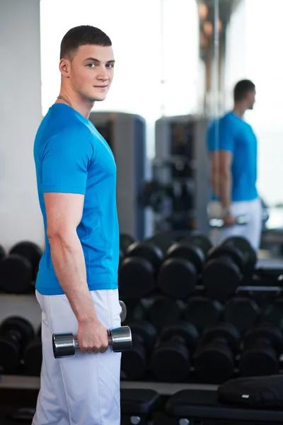 Young guy is engaged with a dumbbell — Stock Photo, Image