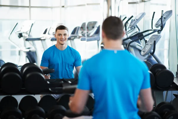 Young sports guy sitting on bench with a dumbbell — Stock Photo, Image