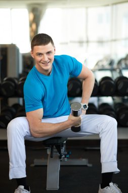 Dambıllarla egzersiz yapan adam.