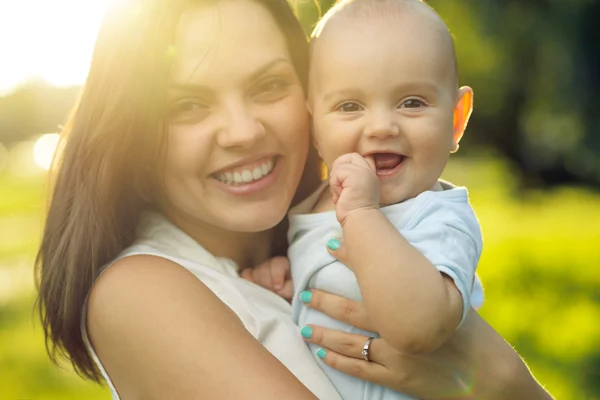 Glad mamma håller en unge son solljus — Stockfoto