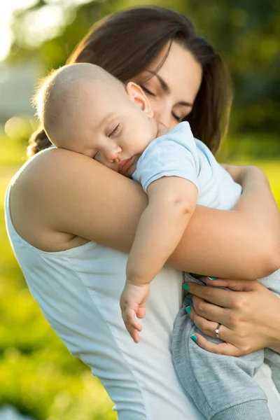 Happy mother holding a young sleeping son — Stock Photo, Image