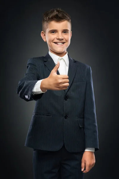 Menino de terno preto mostrando polegares para cima — Fotografia de Stock