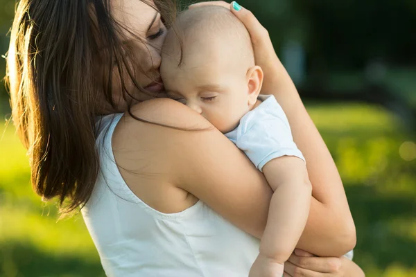 Happy mother holding a young sleeping son — Stock Photo, Image