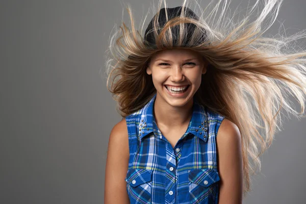 Chica usando un sombrero riendo y su pelo revoloteando — Foto de Stock