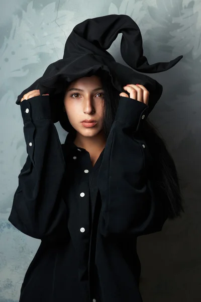 Chica en un disfraz de bruja se ve misteriosamente — Foto de Stock