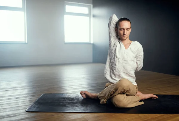 L'homme yogi fait gomukhasana. Pratique du yoga en studio. — Photo