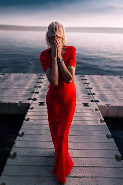 İskelede lüks kırmızı elbiseli çekici genç bir kadın.. — Stok fotoğraf