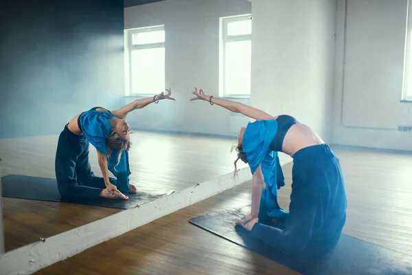 Жінка йоги робить арду уштрасану навпроти дзеркала. Тренування йоги в студії. — стокове фото