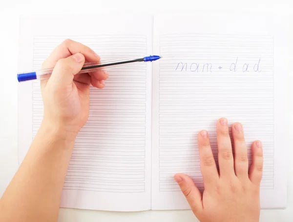 Children.A small child's hand writing in notebook words with a ballpoint pen — Stock Photo, Image